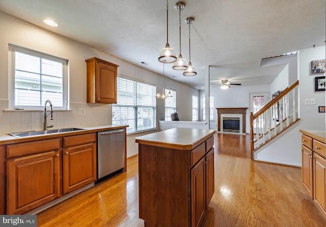 kitchen featuring stainless steel dishwasher, a kitchen island, sink, and light hardwood / wood-style flooring