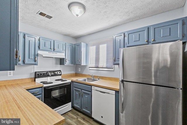 kitchen with blue cabinetry, sink, dark hardwood / wood-style flooring, wooden counters, and white appliances