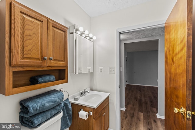 bathroom featuring hardwood / wood-style floors, vanity, a textured ceiling, and toilet