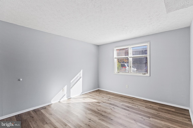 unfurnished room with hardwood / wood-style floors and a textured ceiling