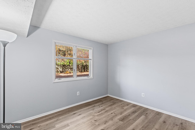 spare room with a textured ceiling and light hardwood / wood-style floors