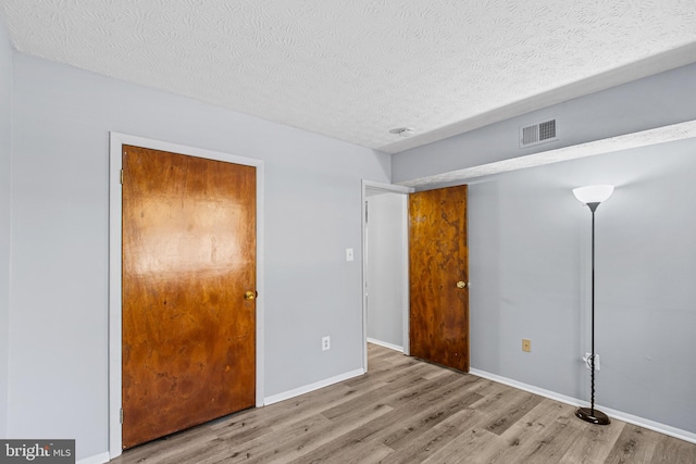 unfurnished bedroom with a textured ceiling and light hardwood / wood-style flooring