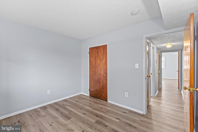 empty room with a textured ceiling and light hardwood / wood-style floors