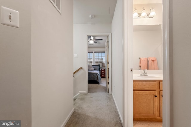 hallway featuring light colored carpet and sink