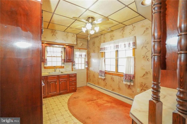 kitchen with ceiling fan, a paneled ceiling, baseboard heating, and sink