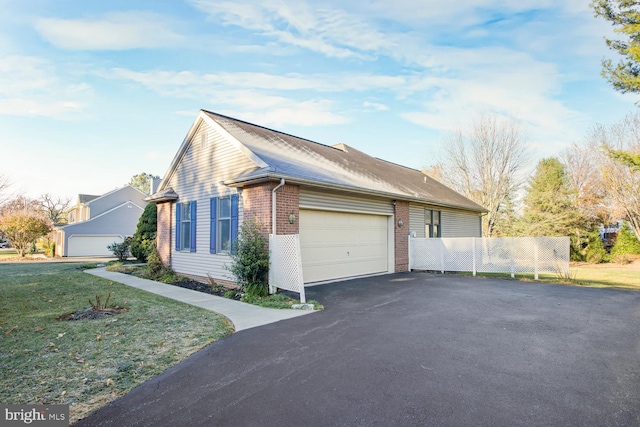 view of side of property featuring a garage and a lawn