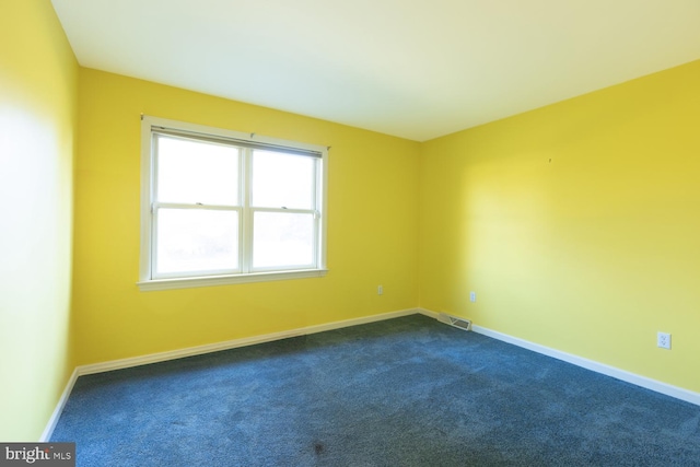 unfurnished room featuring dark colored carpet