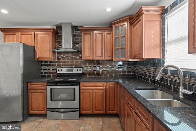 kitchen with decorative backsplash, stainless steel appliances, sink, wall chimney range hood, and dark stone countertops