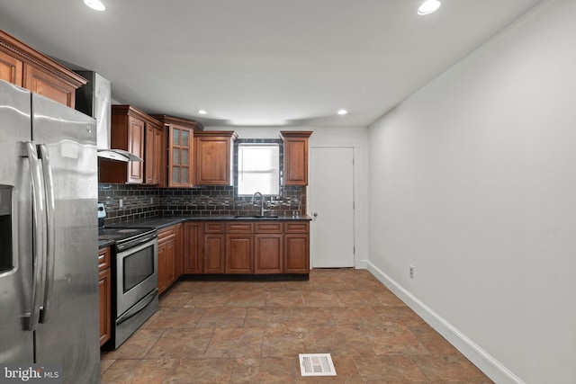 kitchen with backsplash, dark stone counters, sink, wall chimney exhaust hood, and stainless steel appliances