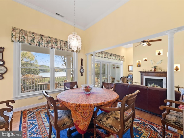 dining space featuring french doors, crown molding, wood-type flooring, a water view, and ceiling fan with notable chandelier