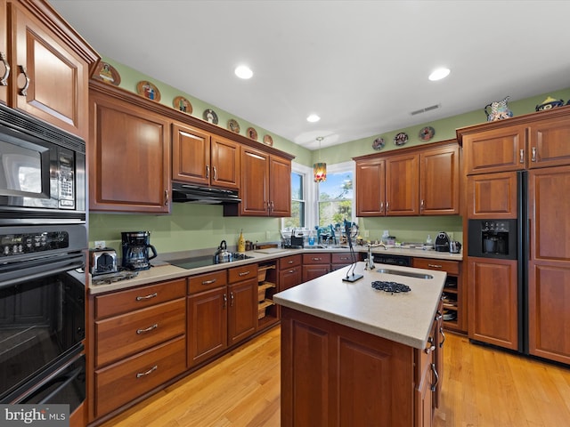 kitchen with pendant lighting, an island with sink, light hardwood / wood-style flooring, and black appliances