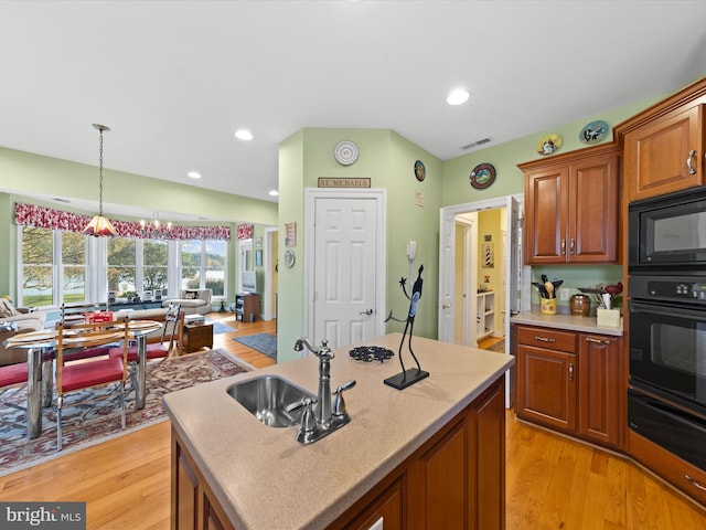 kitchen featuring sink, a center island, black appliances, and light hardwood / wood-style flooring