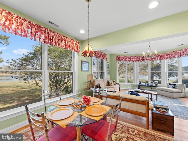 interior space with a notable chandelier, a water view, and a wealth of natural light