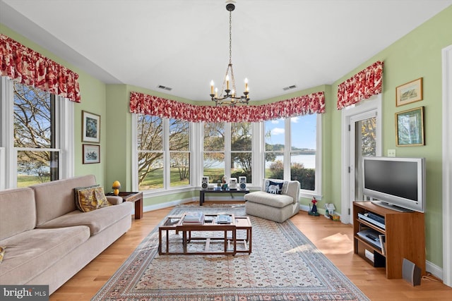 living room featuring a healthy amount of sunlight, an inviting chandelier, and light hardwood / wood-style flooring