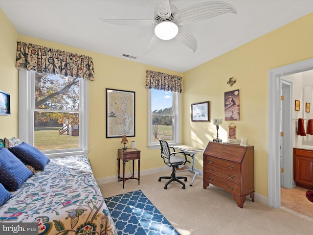 bedroom featuring light colored carpet, ensuite bath, and ceiling fan