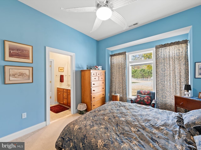 bedroom with ensuite bath, light carpet, and ceiling fan