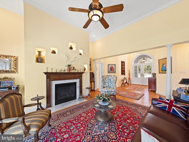 living room featuring ceiling fan, french doors, light hardwood / wood-style flooring, decorative columns, and ornamental molding