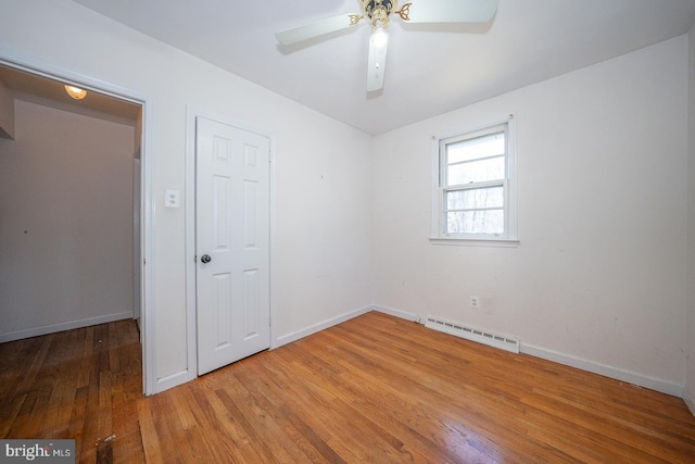 empty room featuring ceiling fan, a baseboard radiator, and hardwood / wood-style flooring