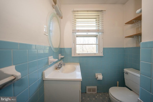 bathroom featuring tile patterned flooring, vanity, tile walls, and toilet