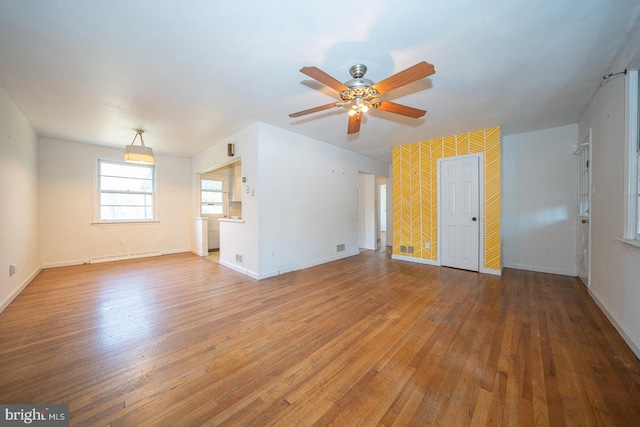 empty room featuring hardwood / wood-style floors, ceiling fan, and a baseboard heating unit