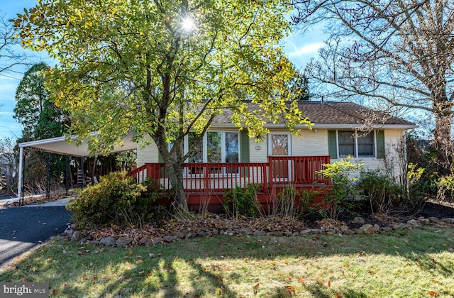 view of front of home with a carport, a front yard, and a wooden deck