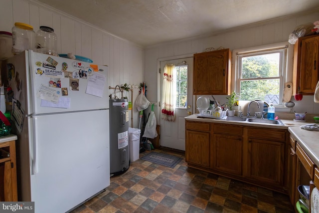 kitchen featuring sink, white fridge, crown molding, and water heater