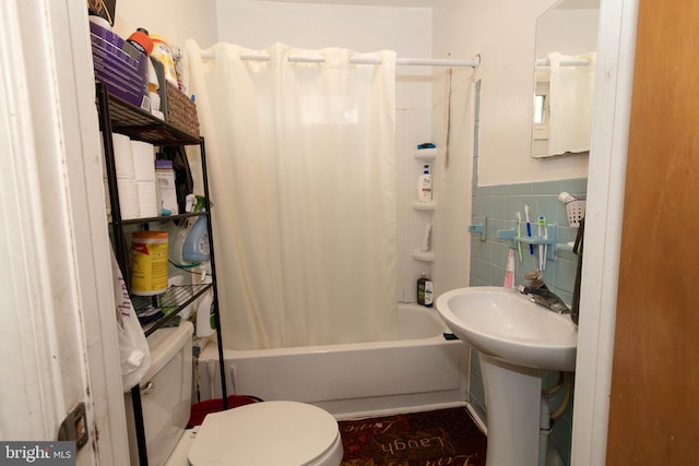 bathroom with toilet, tile walls, and shower / tub combo with curtain