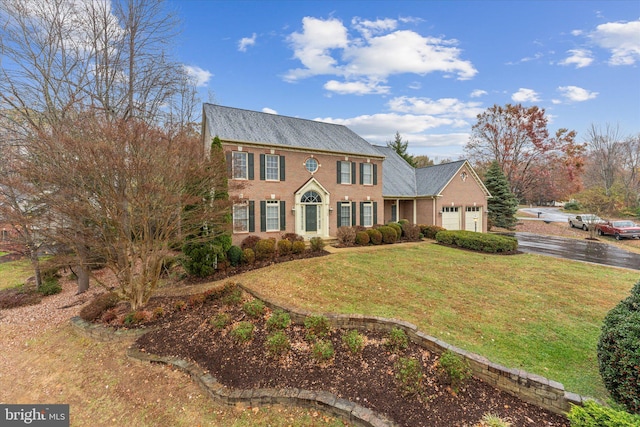 colonial home featuring a garage and a front lawn