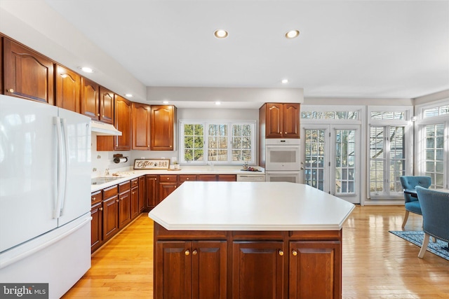 kitchen featuring a center island, white appliances, and light hardwood / wood-style flooring