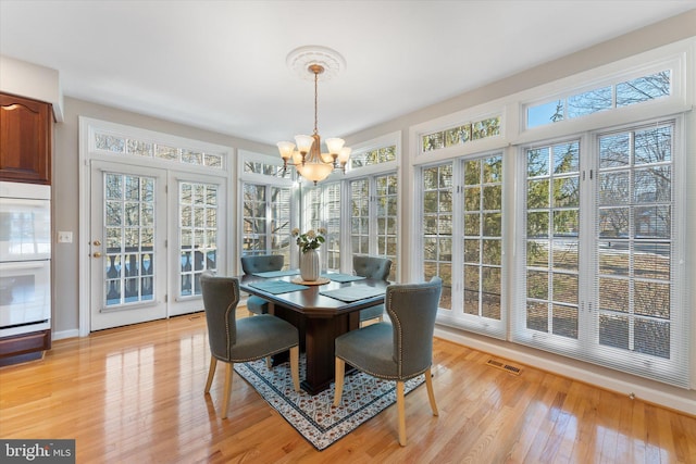 dining area with a notable chandelier and light hardwood / wood-style floors