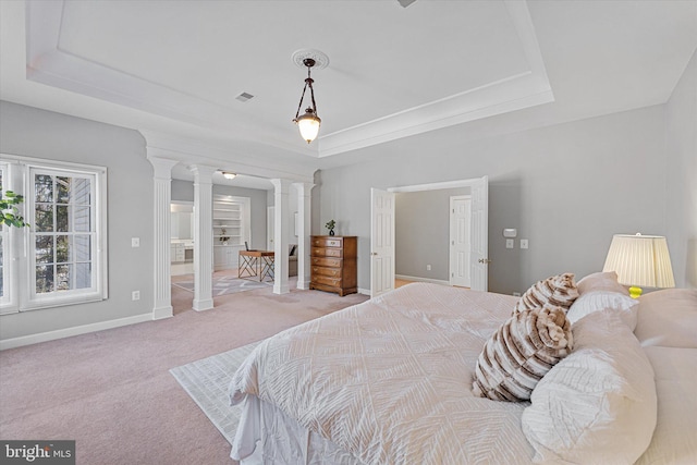 carpeted bedroom with a raised ceiling and ornate columns