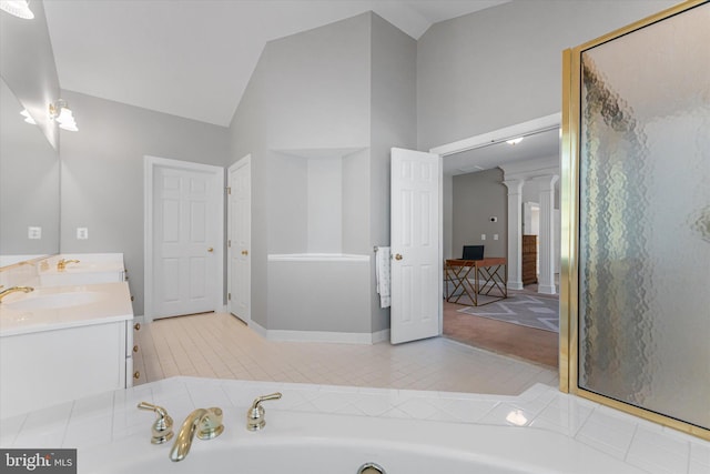 bathroom featuring lofted ceiling, vanity, a washtub, and ornate columns