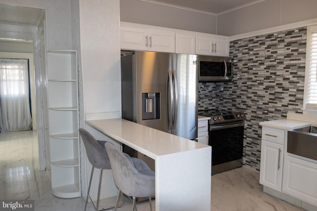 kitchen with kitchen peninsula, a kitchen breakfast bar, stainless steel appliances, crown molding, and white cabinets