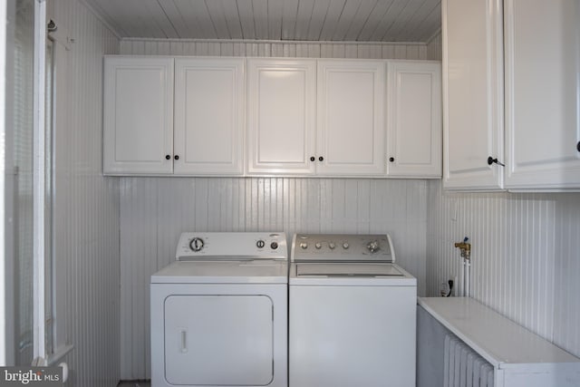 laundry area with washer and clothes dryer, cabinets, and wooden walls