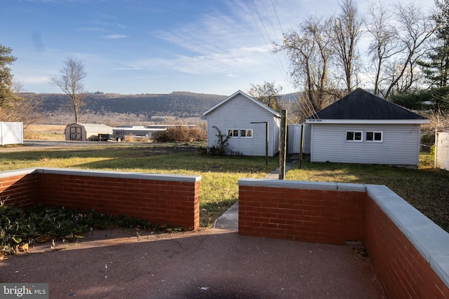 view of home's exterior with a mountain view, a storage shed, and a yard