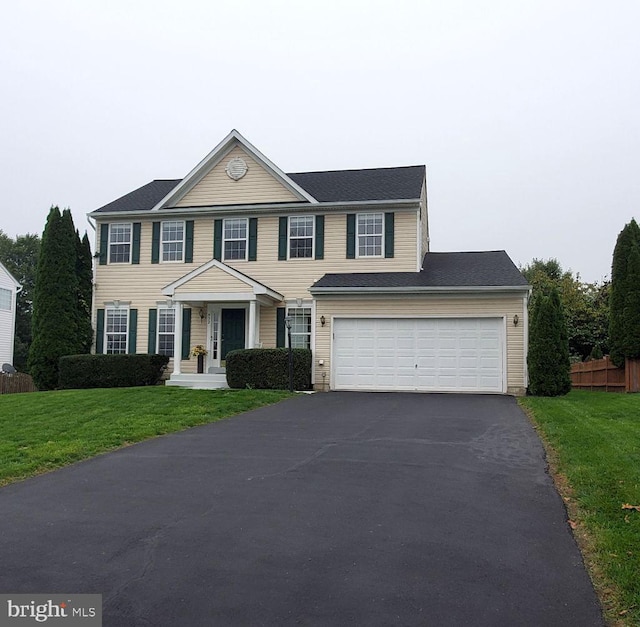 colonial home with a garage and a front lawn