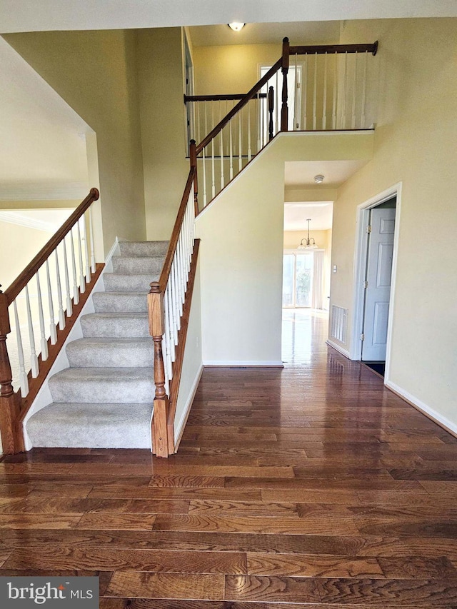 stairway with hardwood / wood-style floors and a towering ceiling