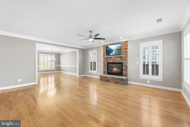 unfurnished living room with ceiling fan with notable chandelier, a healthy amount of sunlight, and light hardwood / wood-style floors