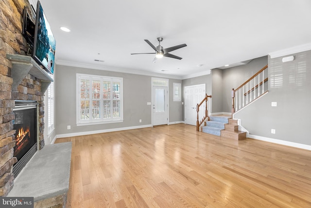 unfurnished living room with a stone fireplace, crown molding, ceiling fan, and light wood-type flooring