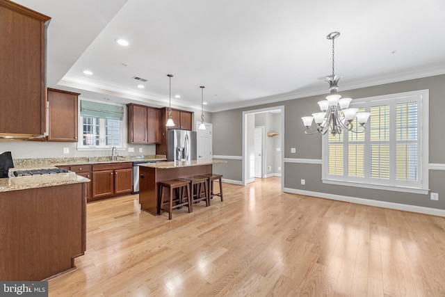 kitchen featuring sink, stainless steel appliances, light hardwood / wood-style flooring, pendant lighting, and a kitchen island