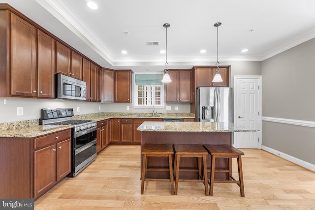 kitchen featuring a center island, stainless steel appliances, hanging light fixtures, and light hardwood / wood-style floors