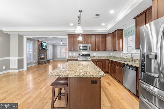 kitchen with sink, a center island, stainless steel appliances, light hardwood / wood-style flooring, and a fireplace