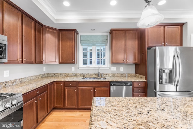 kitchen featuring light stone countertops, sink, stainless steel appliances, pendant lighting, and light hardwood / wood-style floors