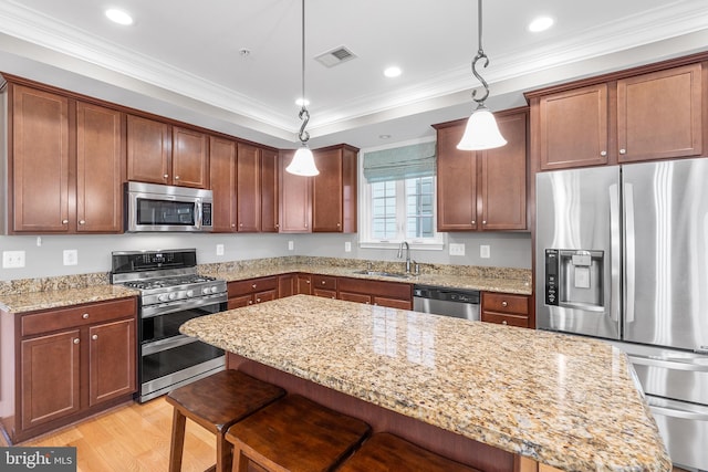 kitchen featuring sink, stainless steel appliances, light hardwood / wood-style floors, pendant lighting, and ornamental molding