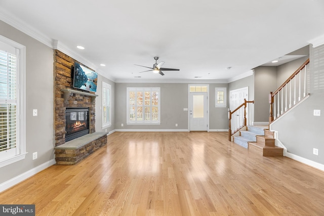 unfurnished living room featuring light hardwood / wood-style flooring, ceiling fan, crown molding, and a stone fireplace