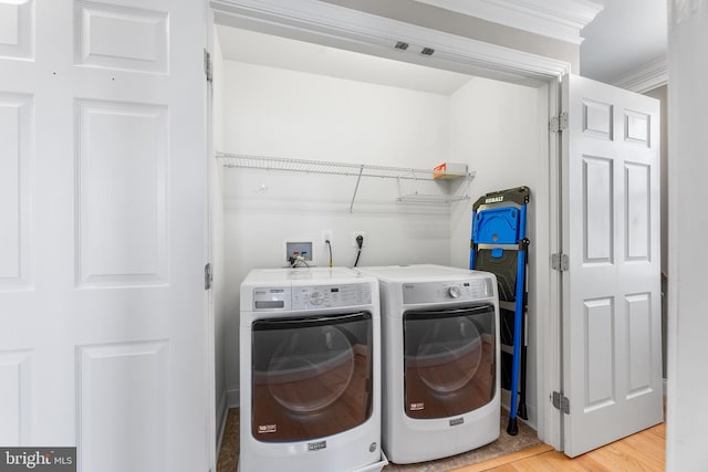 laundry room featuring separate washer and dryer, crown molding, and hardwood / wood-style flooring