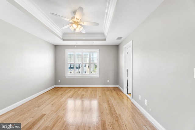 unfurnished room with light wood-type flooring, a tray ceiling, ceiling fan, and ornamental molding