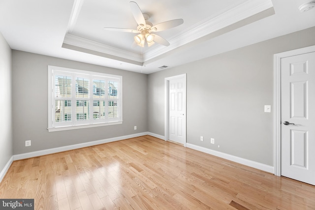 spare room featuring ceiling fan, a raised ceiling, crown molding, and light hardwood / wood-style flooring