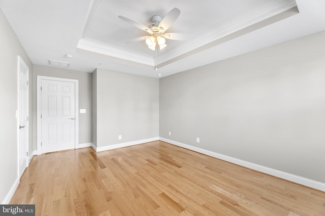 unfurnished room with a tray ceiling, ceiling fan, crown molding, and light wood-type flooring