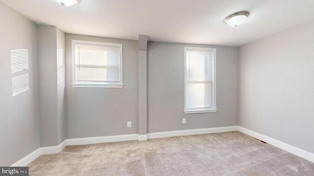 unfurnished room featuring a wealth of natural light and light colored carpet